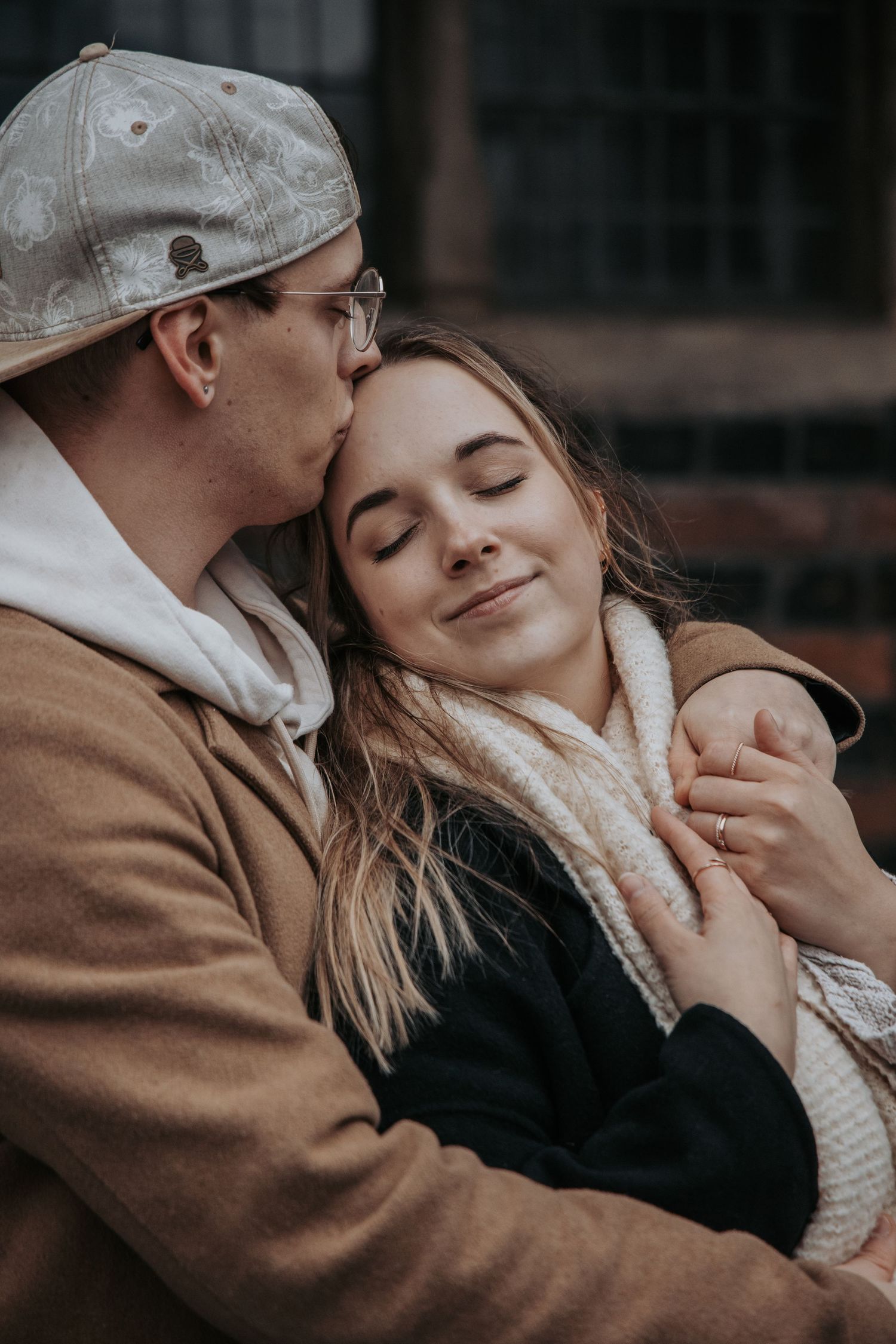 A tender moment between a couple embracing outdoors on a moody autumn day with soft lighting and warm clothing.