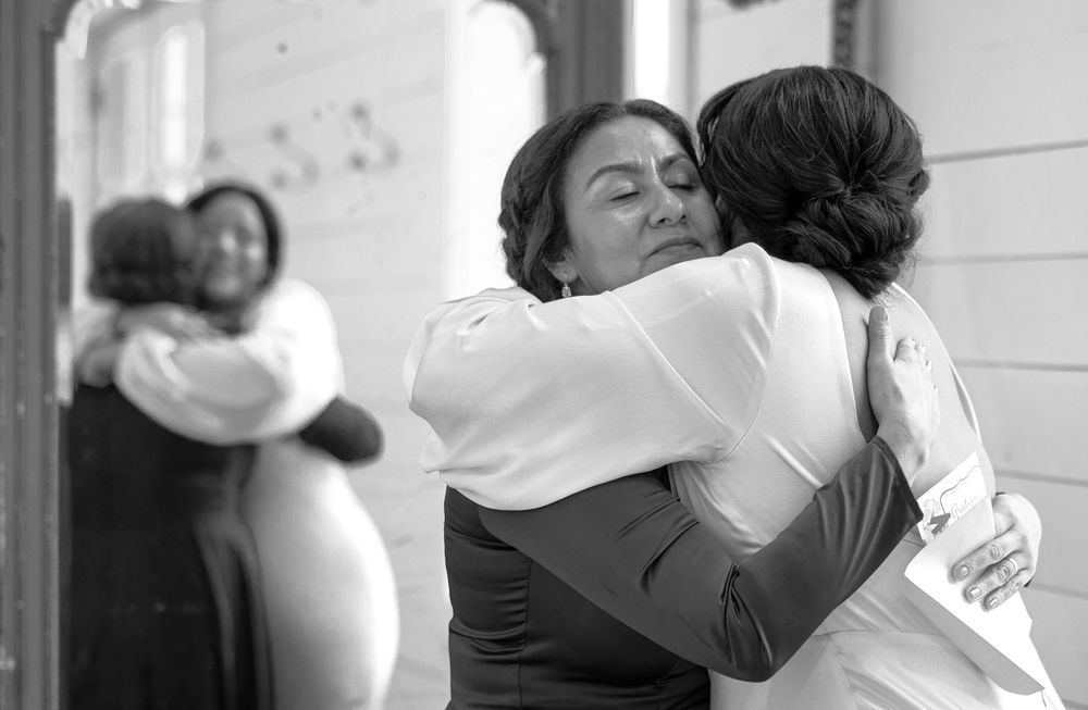 Emotional black and white photo of a bride sharing a heartfelt hug with a guest at her wedding.