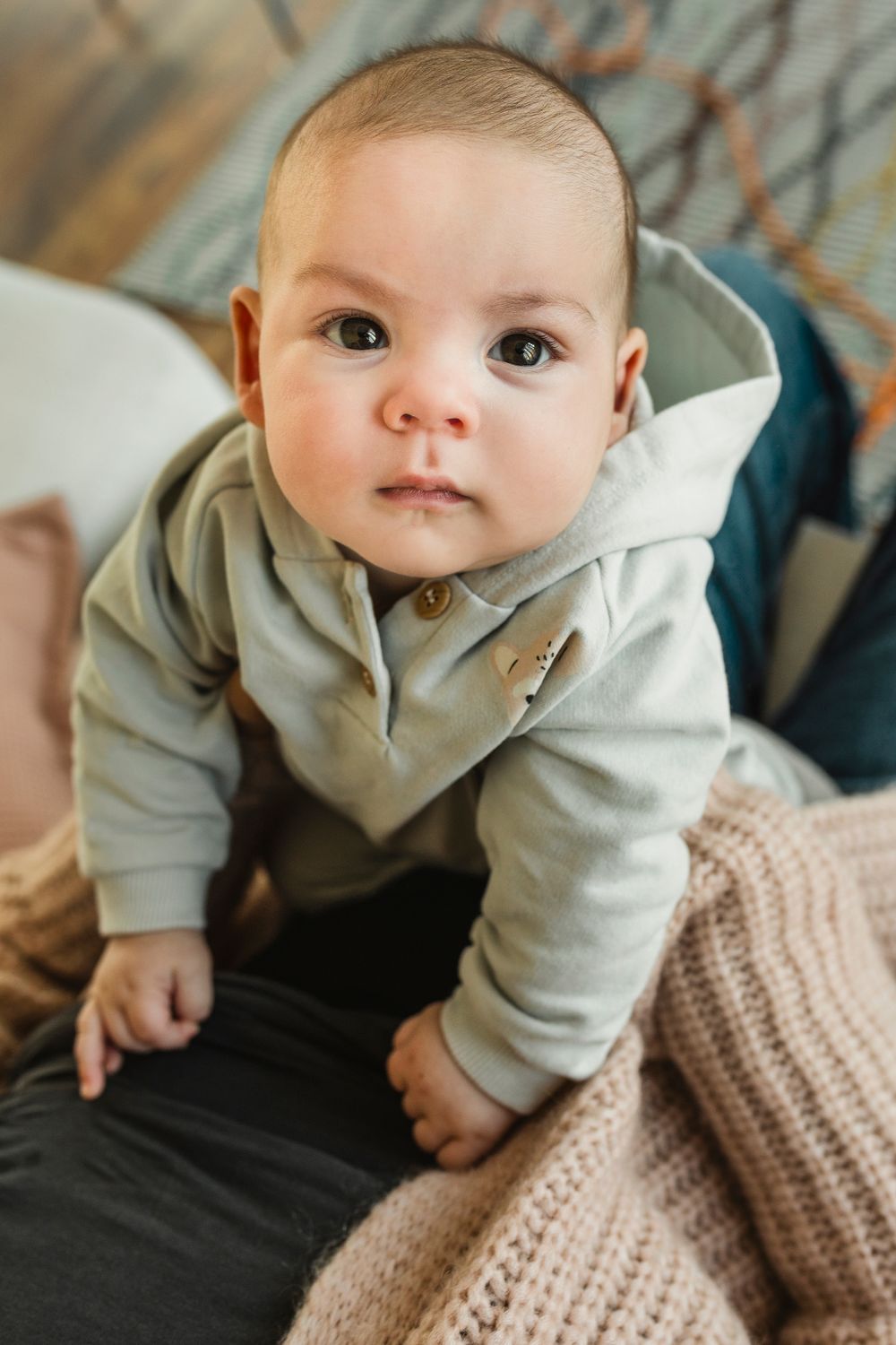 Fotografía de moda bebé sentado con su  mamá en sofá con ropa de BEANS en Barcelona