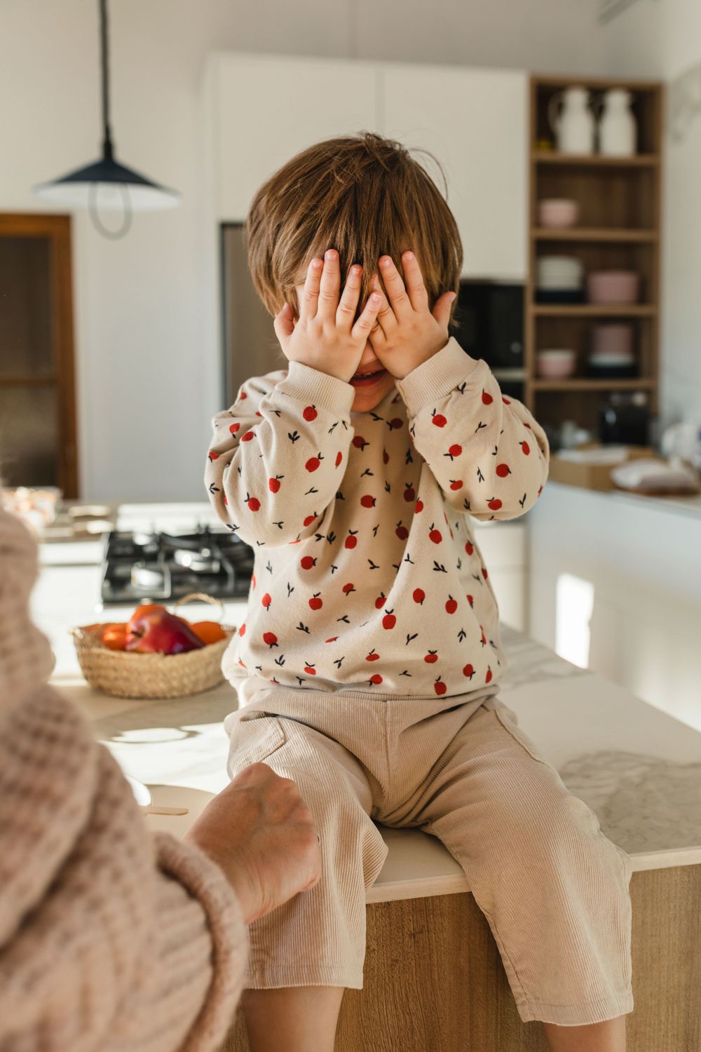 Fotografía de moda niño sentado con su  mamá en cocina con ropa de BEANS en Barcelona