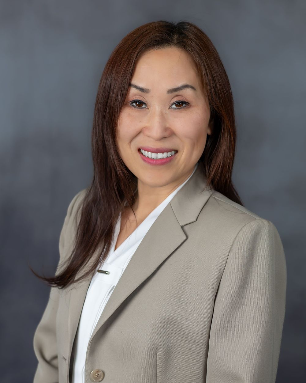 Professional headshots showing someone in a beige blazer and white blouse against a gray studio backdrop.