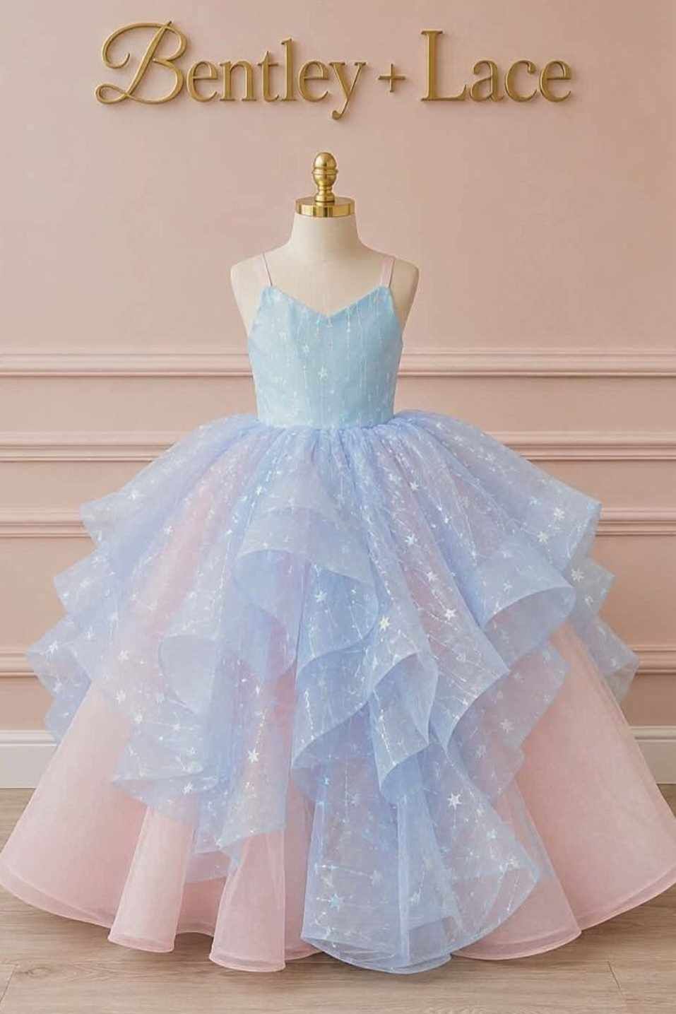 Child in flowing ice blue gown poses in magical winter wonderland scene with frozen castle backdrop and snowy stairs.