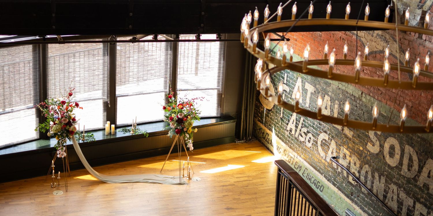 Sunlight streams through windows in rustic event space with vintage decor and floral arrangements.