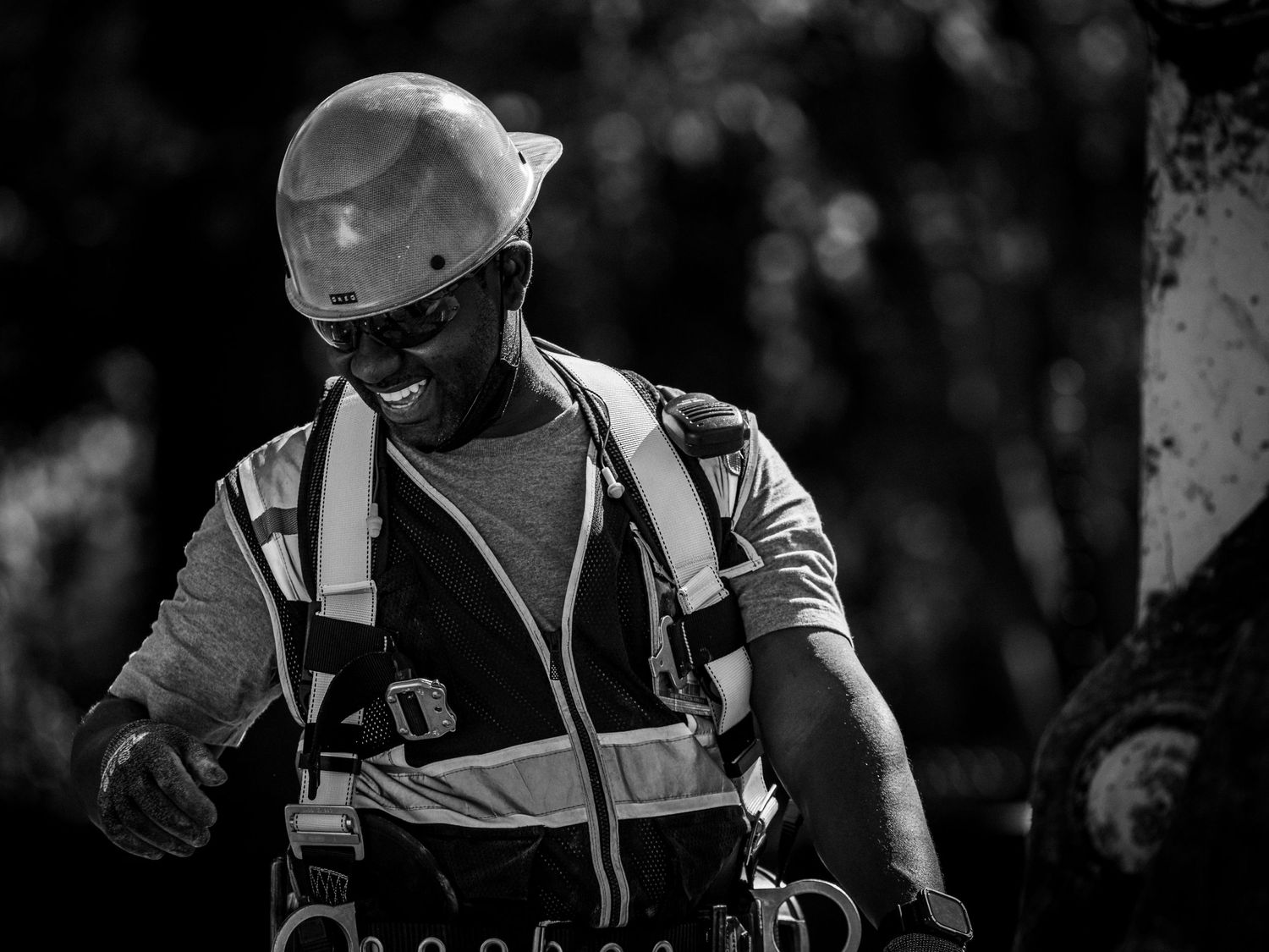 Construction worker in safety gear and hard hat working on site shown in black and white photography.