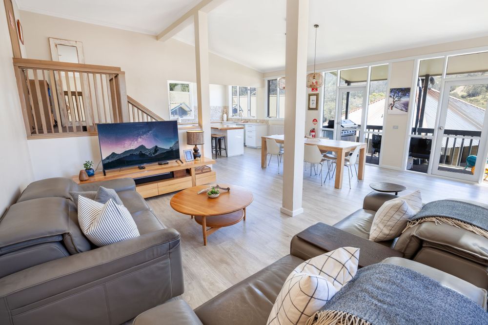Contemporary living room with grey couches and mountain artwork featuring an open-concept design.