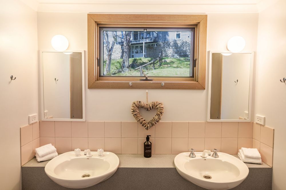 Elegant bathroom vanity with dual sinks, framed artwork and heart-shaped wall decoration.