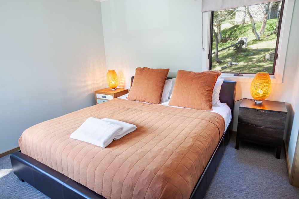 Cozy bedroom with peach-colored bedding, white pillows and bedside lamps creating warm ambiance.