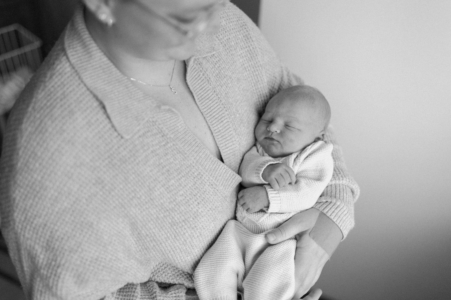 Black and white photo of a newborn being held in cozy sweater.  Virginia/ North Carolina Newborn First 48 Hours Session