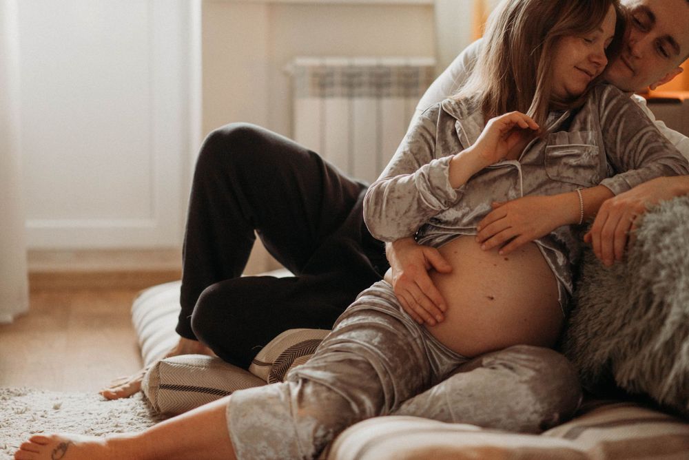 Intimate maternity photo of couple relaxing together on couch during pregnancy session.