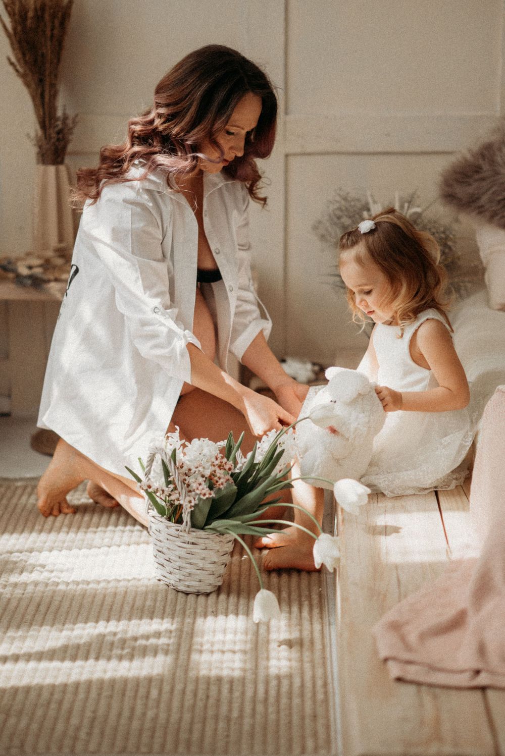 Sunlit scene of gentle moments with flowers and white dresses.