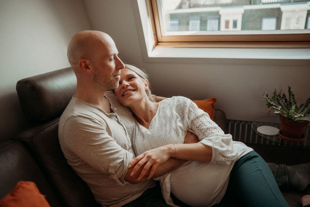 Intimate lifestyle photography captures quiet moments on a living room couch near a window.