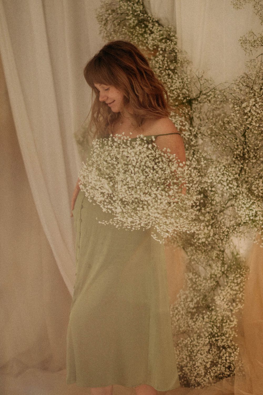 Ethereal portrait with baby's breath flowers and flowing fabric in warm tones.