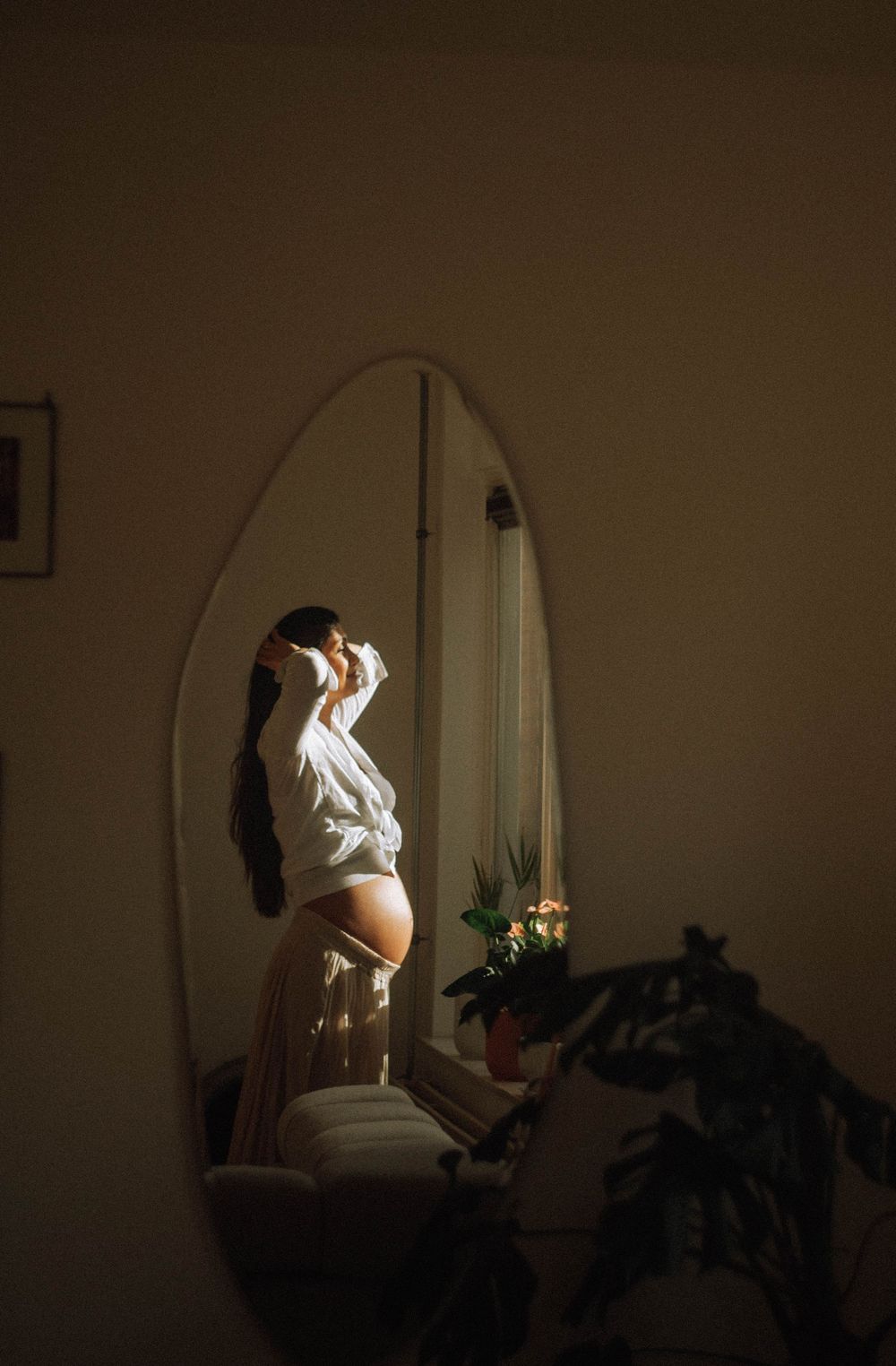 Artistic silhouette photos of a pregnant woman in a dimly lit room with mirror.