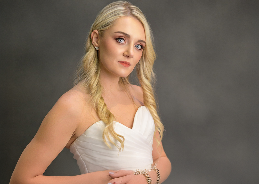 Figure in white formal dress against dark background.
