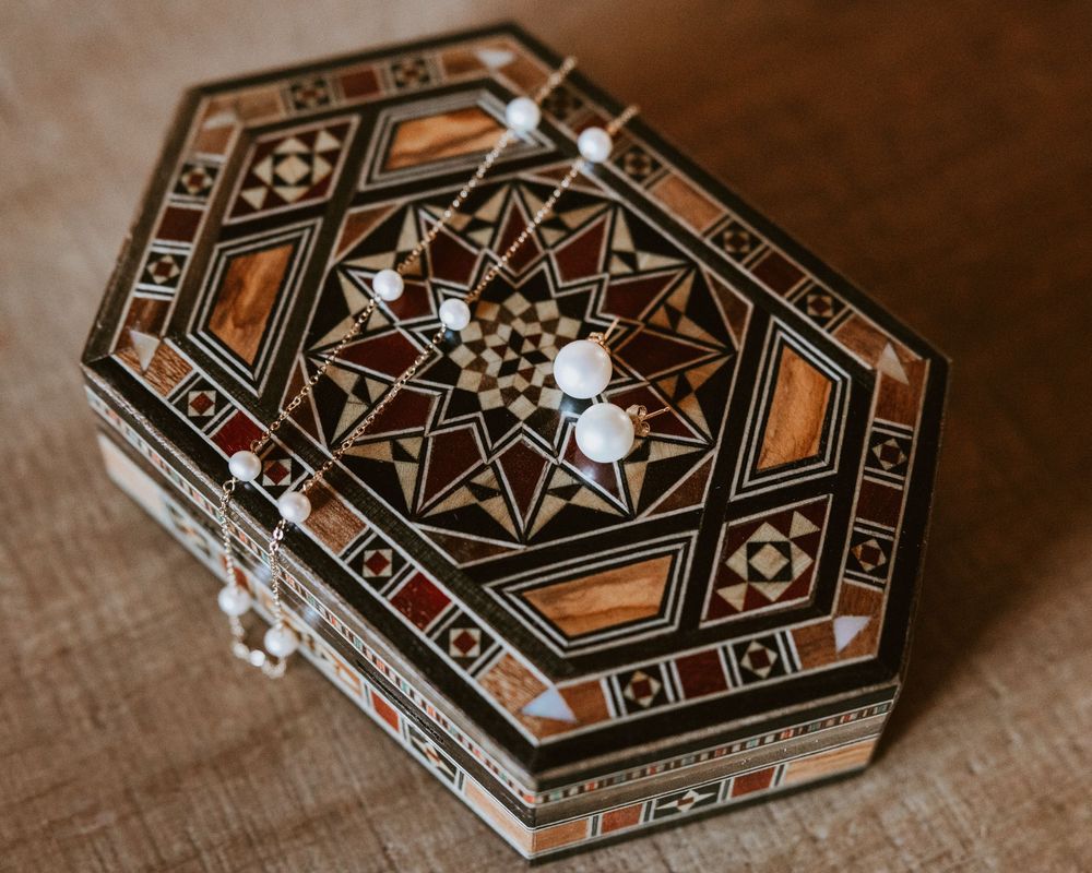 Intricate hexagonal wooden mosaic jewelry box with geometric star pattern and pearl accents.
