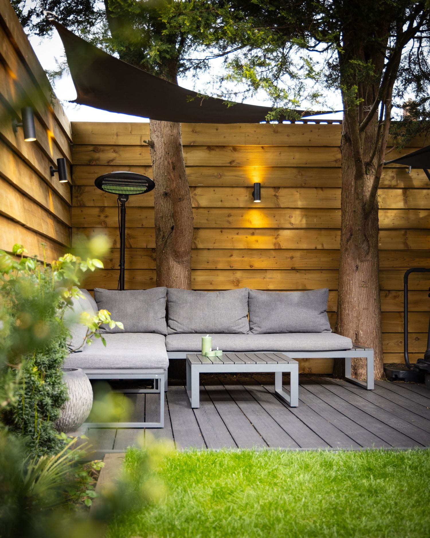 Modern spa patio in Bedfordshire with sectional seating, shade sail and greenery, photographed during exterior shoot.