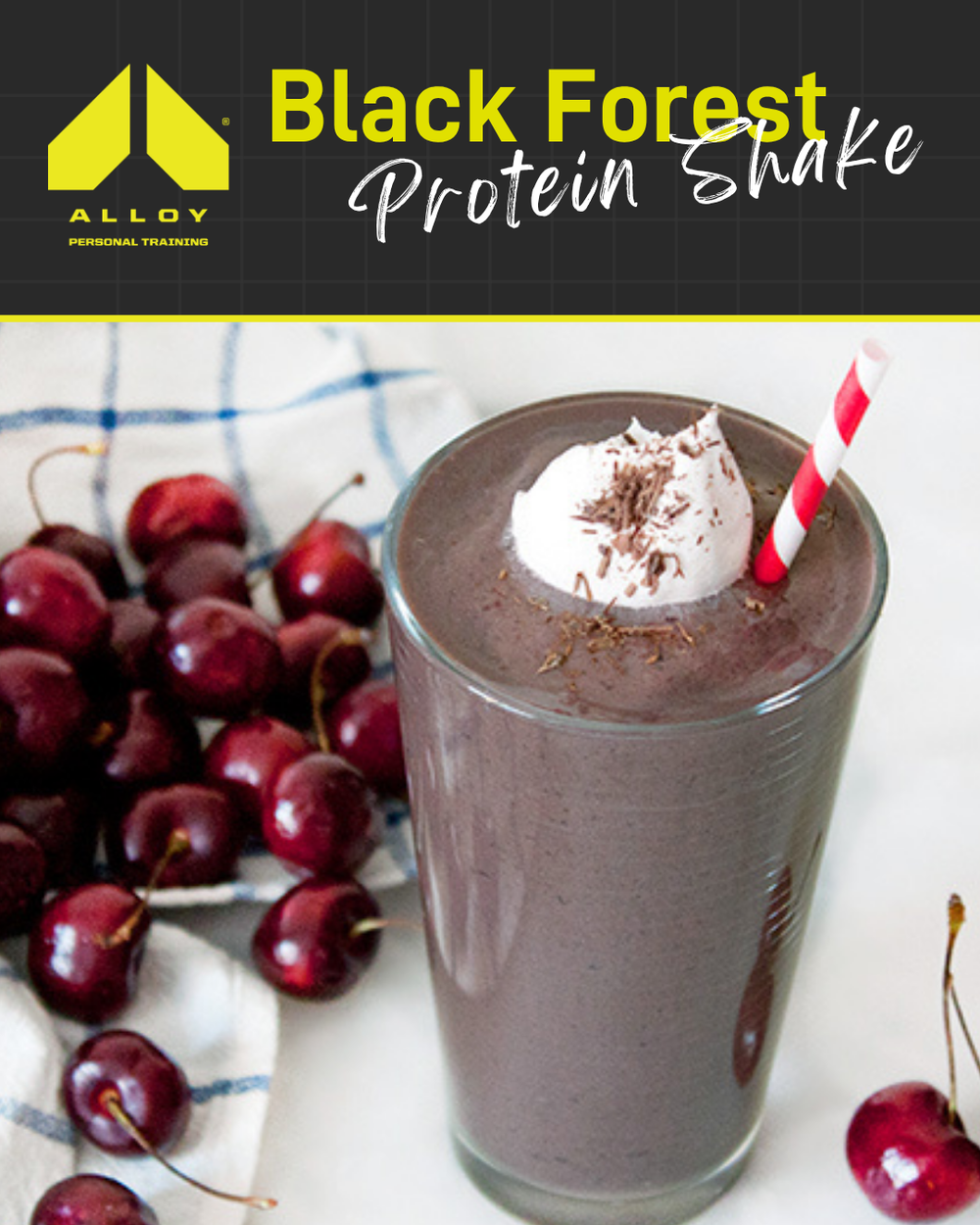 Alloy Personal Training Black Forest Protein Shake in a glass with whipped cream, chocolate shavings, a straw, and fresh cherries.