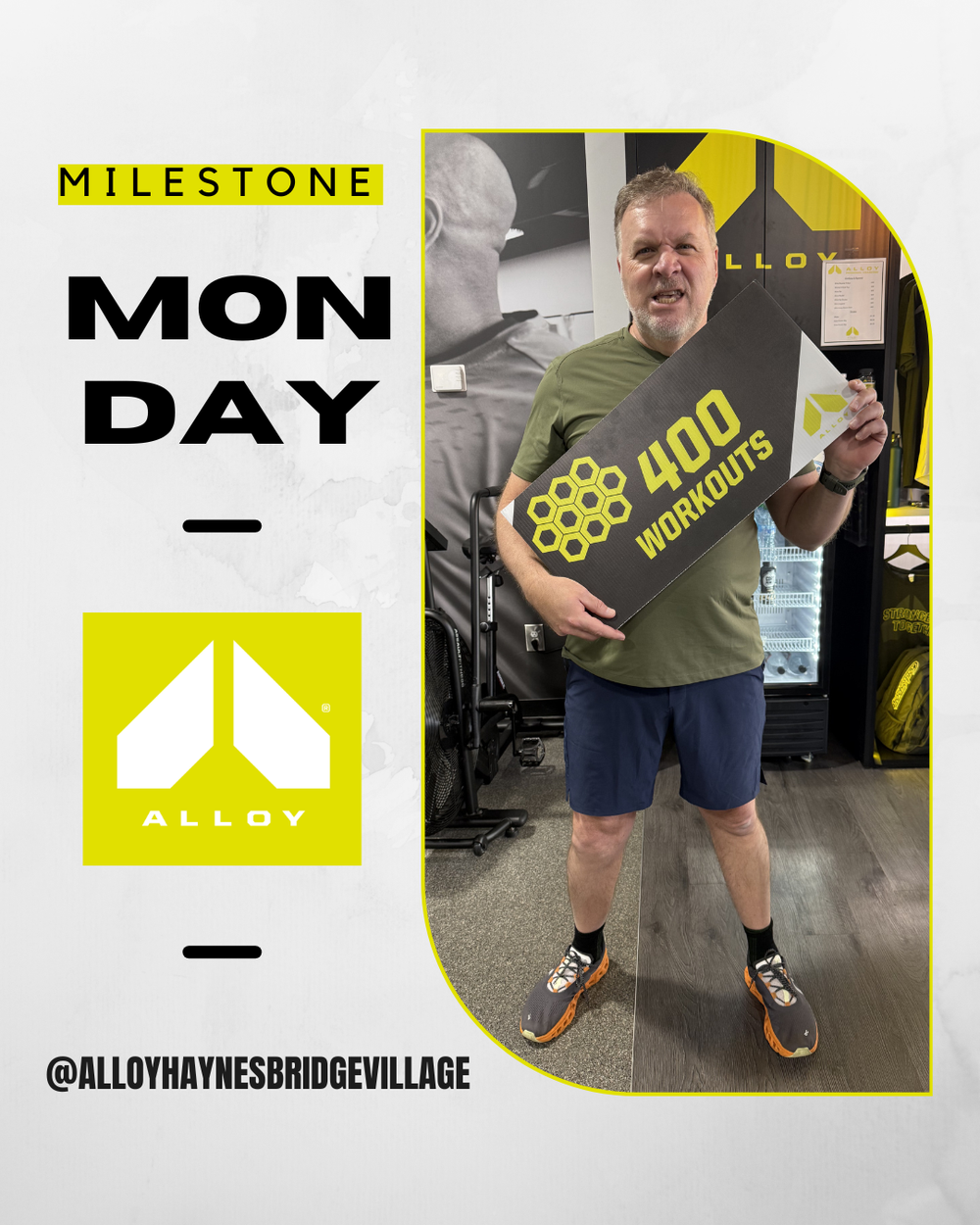 Man celebrating 400 workouts milestone at Alloy Haynes Bridge Village gym, holding a sign on Monday.
