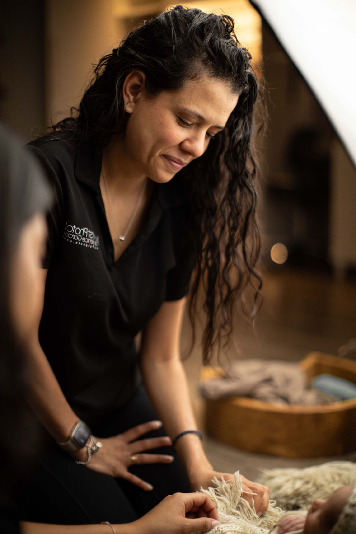 Woman in black uniform carefully tending to a newborn baby during a professional photography session.