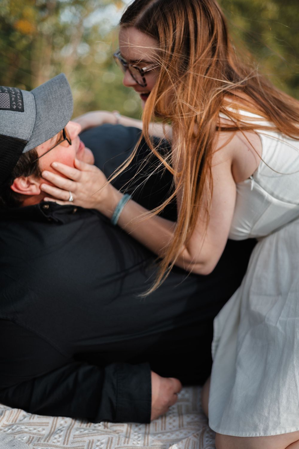 A playful and genuine lifestyle portrait of a couple sharing a quiet moment on a picnic blanket in an open field near Buda, Texas.