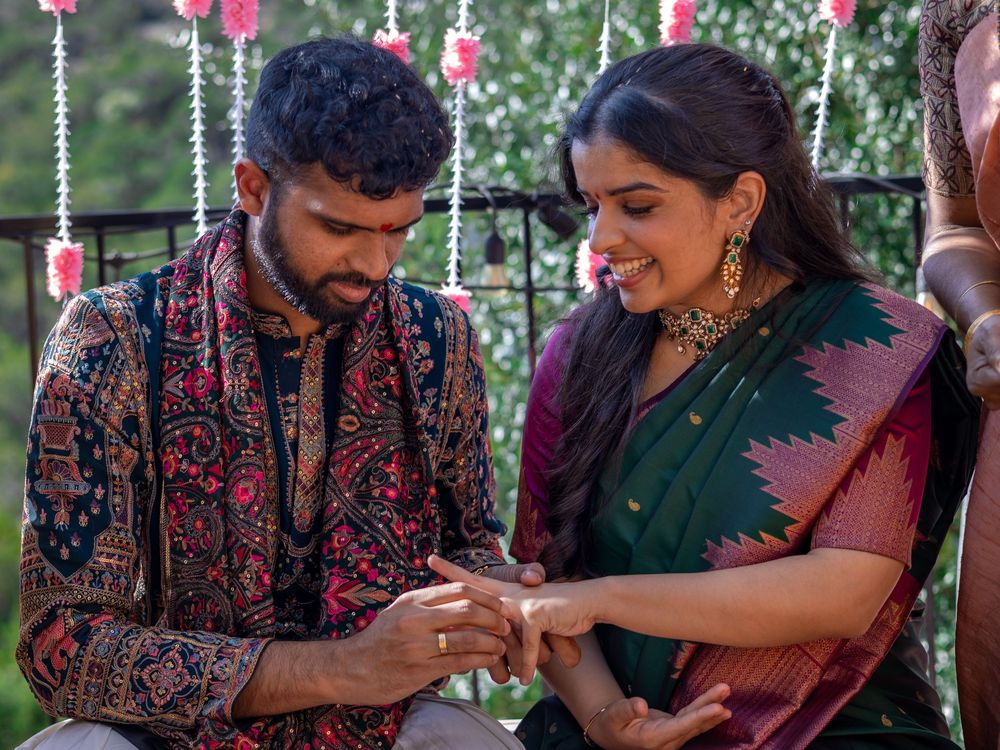 Editorial wedding photography capturing the intimate moment of a groom placing a ring on the bride's finger during a traditional ceremony.
