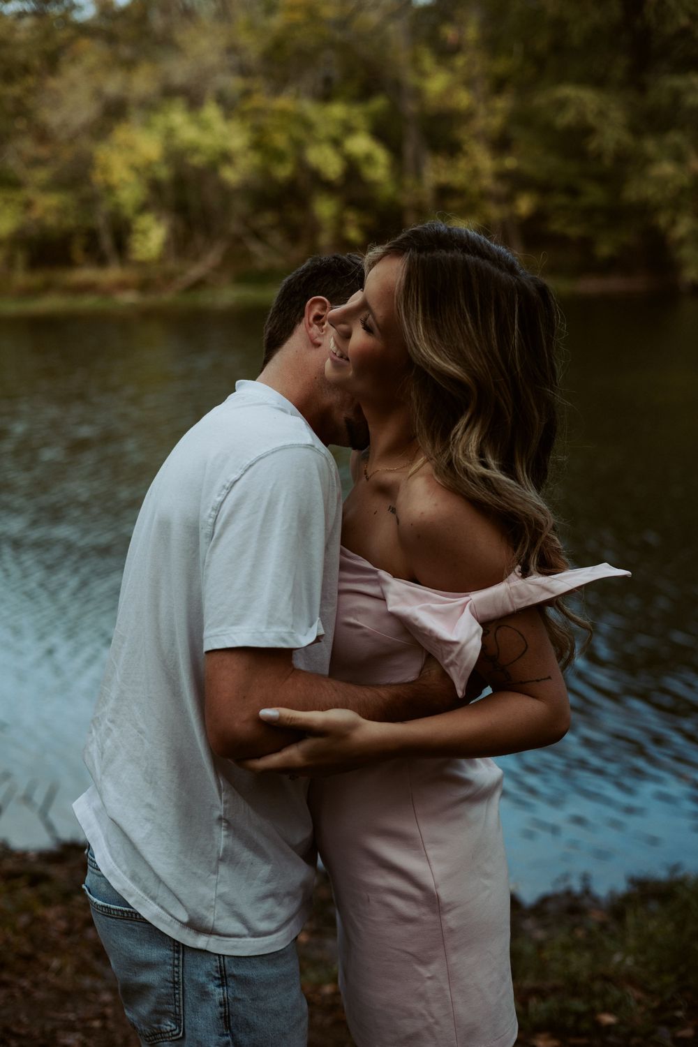 An intimate and refined "Love Stories" portrait of a couple embracing near a lakeside setting in Central Texas.