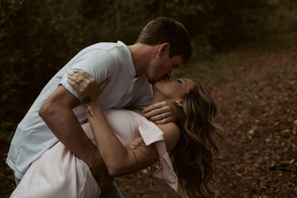 A romantic and editorial wedding portrait of a couple kissing in a wooded area, captured with a natural and storytelling aesthetic.