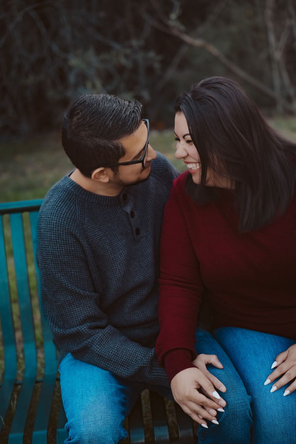 An intimate and natural lifestyle portrait of a couple sitting on a bench in a wooded Central Texas setting.