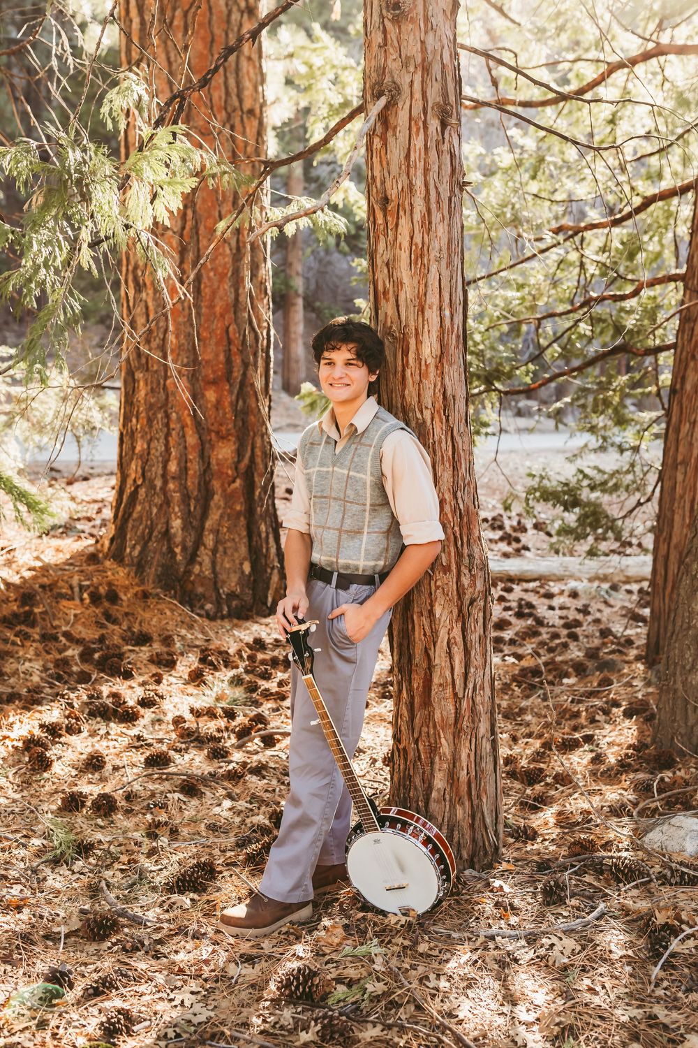 graduating senior boy stands next to his banjo during senior photos with family photographer heidi grace photography