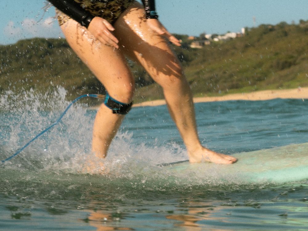 close up action shot of female surfer turning her longboard with Sunlight Surfers social surf Dudley
