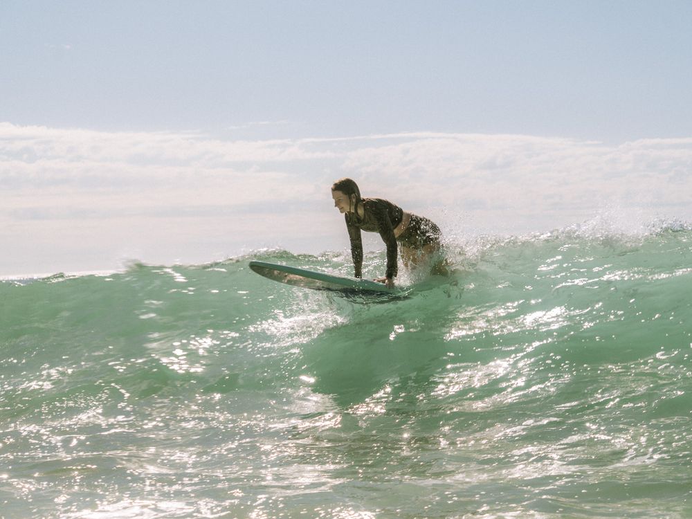 beginner surfer kneeling on a steep wave on a group social surf with Sunlight Surfers Dudley Newcastle NSW