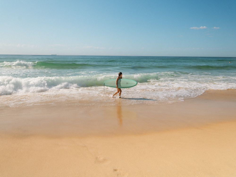 photo of a surfer coming out from the surf with Sunlight Surfers Dudley Newcastle NSW