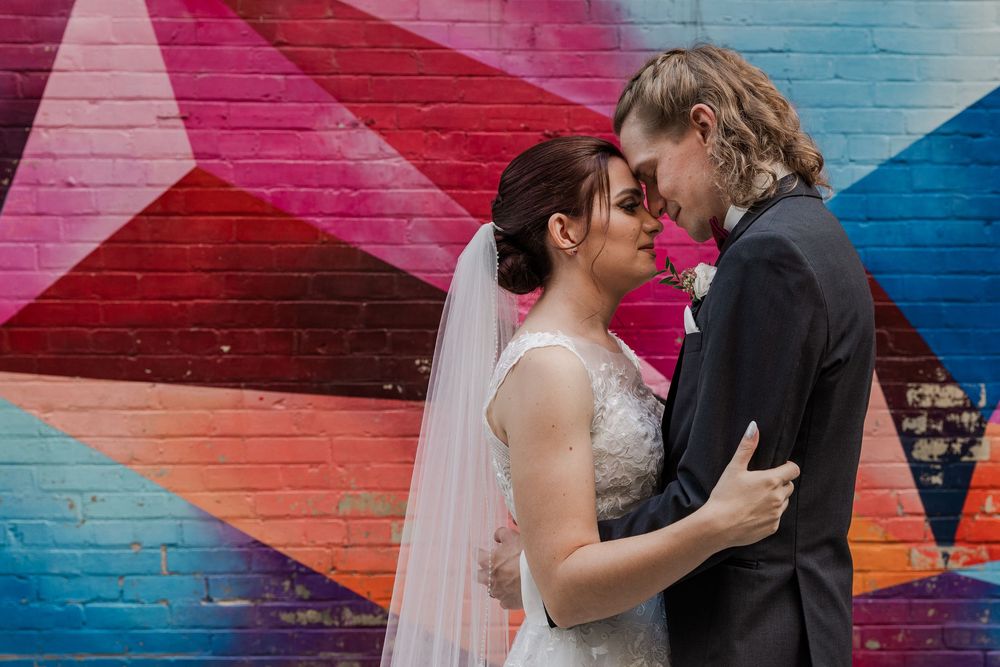 Bride and groom rest their foreheads together in front of some colourful graffiti in an alley near the Walper hotel in Kitchener, Ontario.
