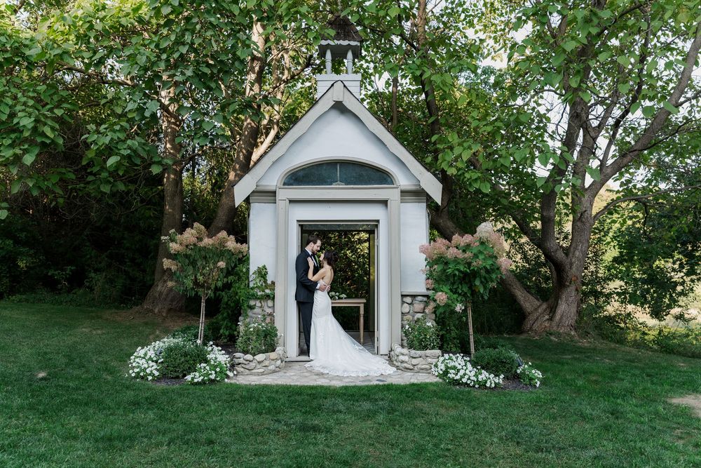 Bride and goom lean into each other in the doorway of a mini chapel building at the Wren House in St. Jacobs, Ontario.