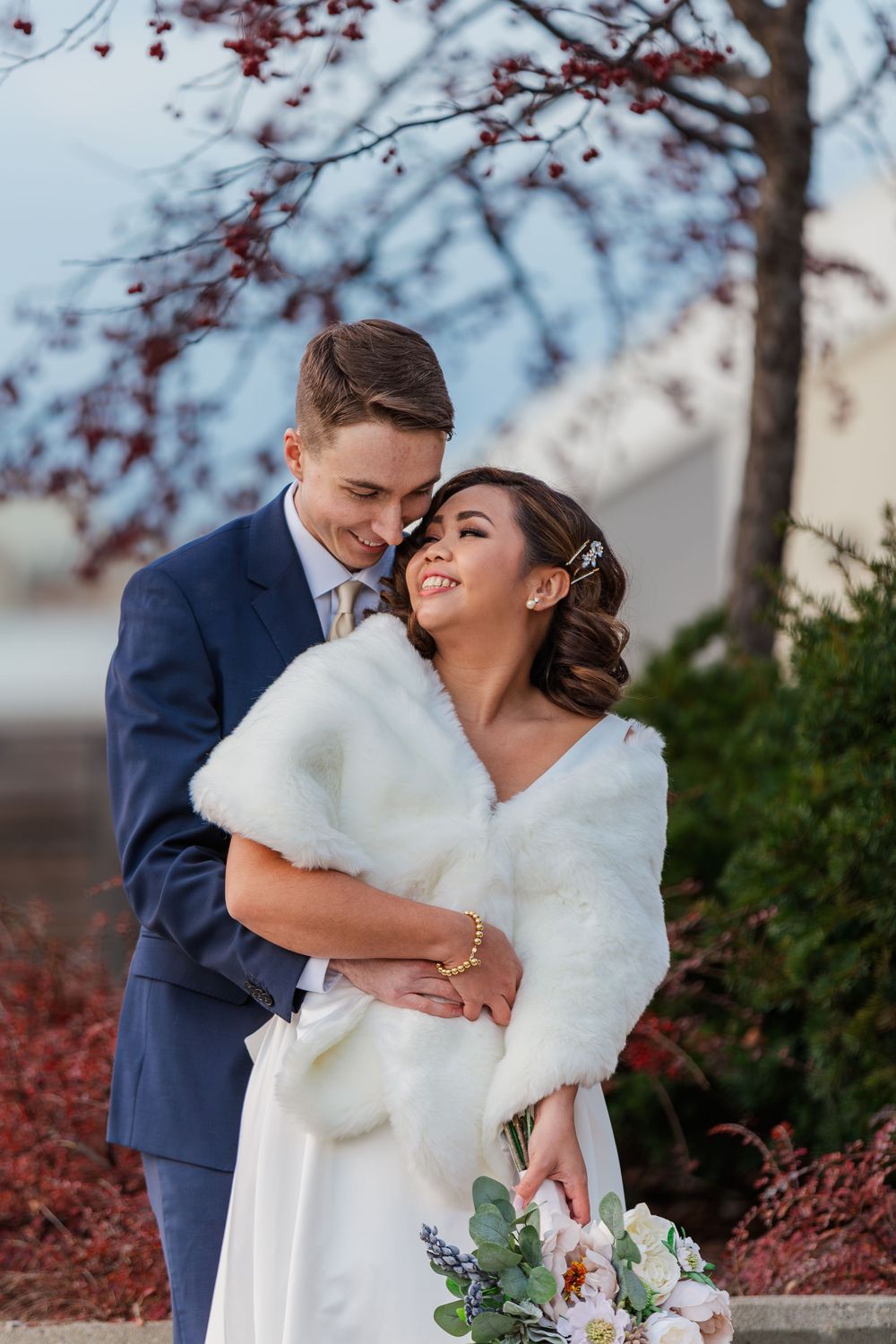 Groom holds his bride close as they look at each other in the winter gardens around uptown waterloo, Ontario.