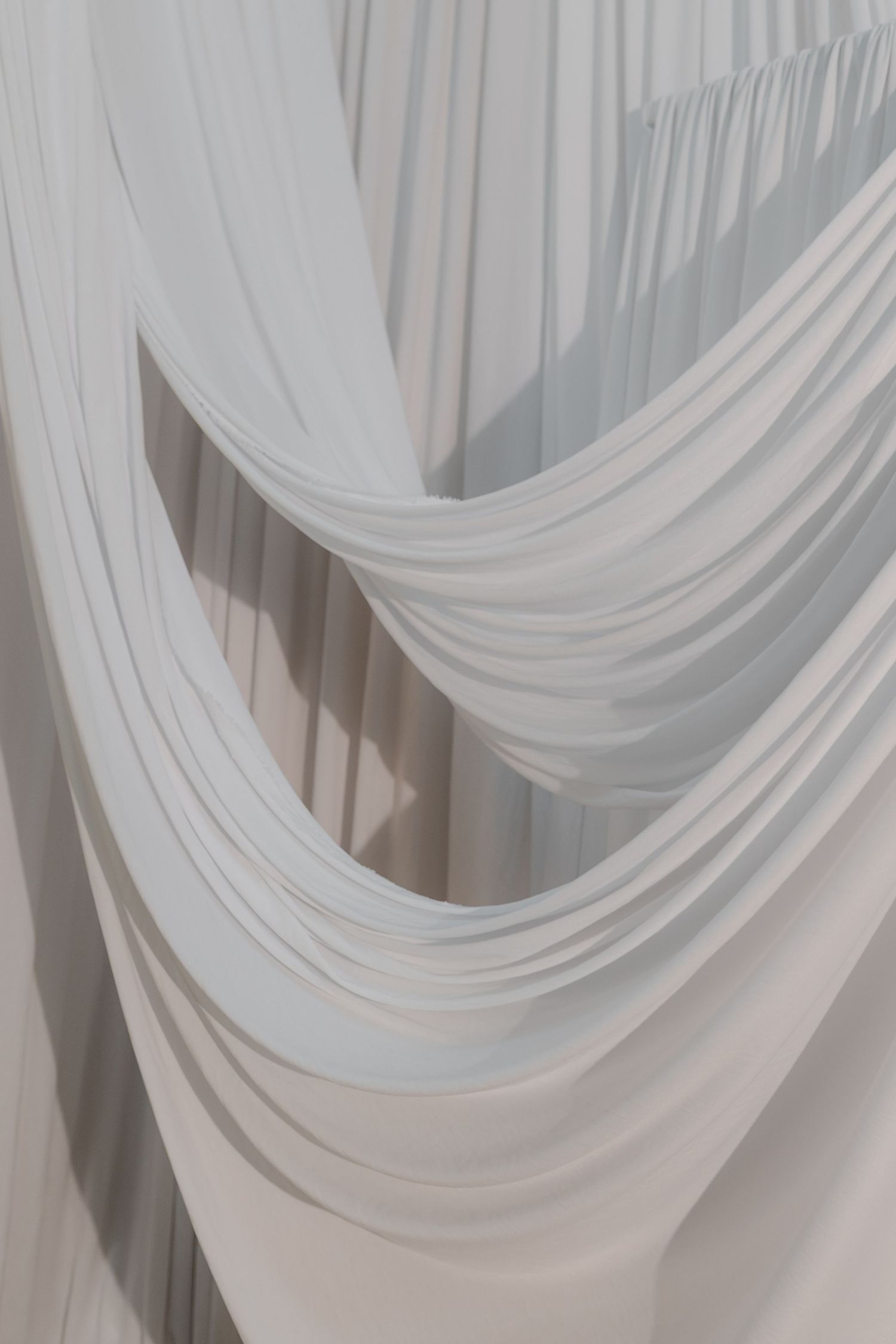 Elegant white draped fabric curtains with soft flowing folds creating a luxurious wedding venue backdrop.