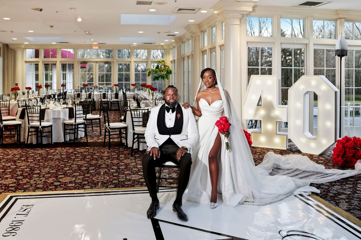 Elegant wedding couple posing on dance floor in decorated ballroom with marquee numbers and floral arrangements. Deerfield Golf Club Newark