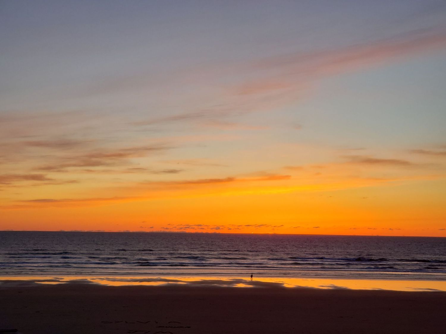 Ocean sunset with vibrant orange sky over water, peaceful coastal scene