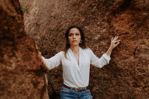 woman poses between large boulders with sunset in background