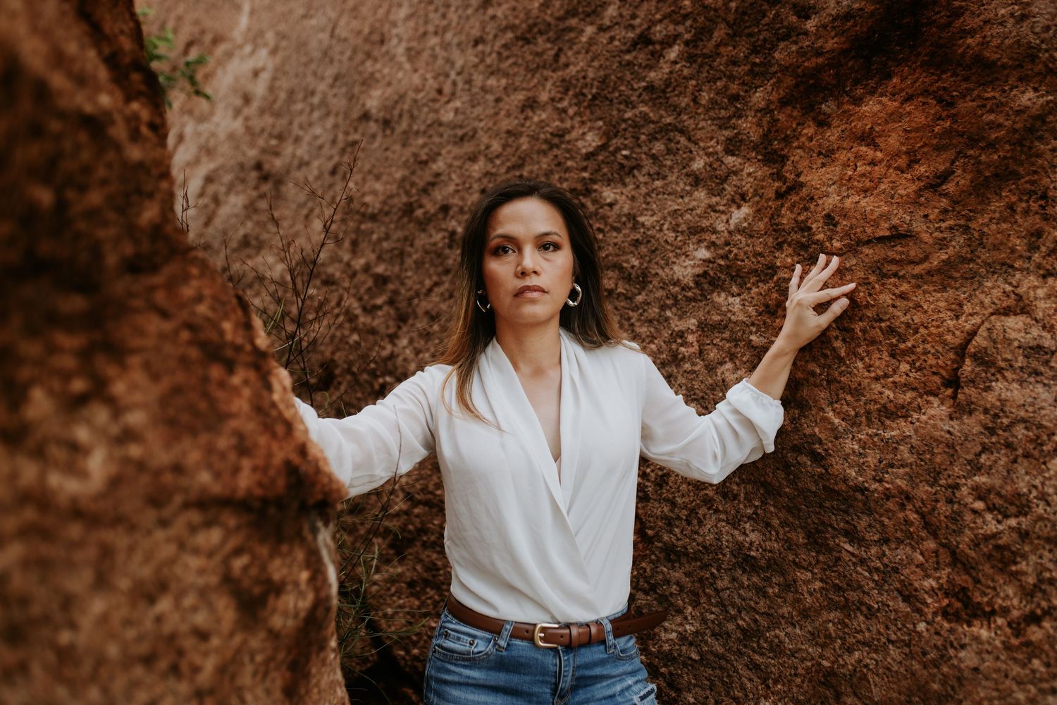 woman poses between large boulders with sunset in background