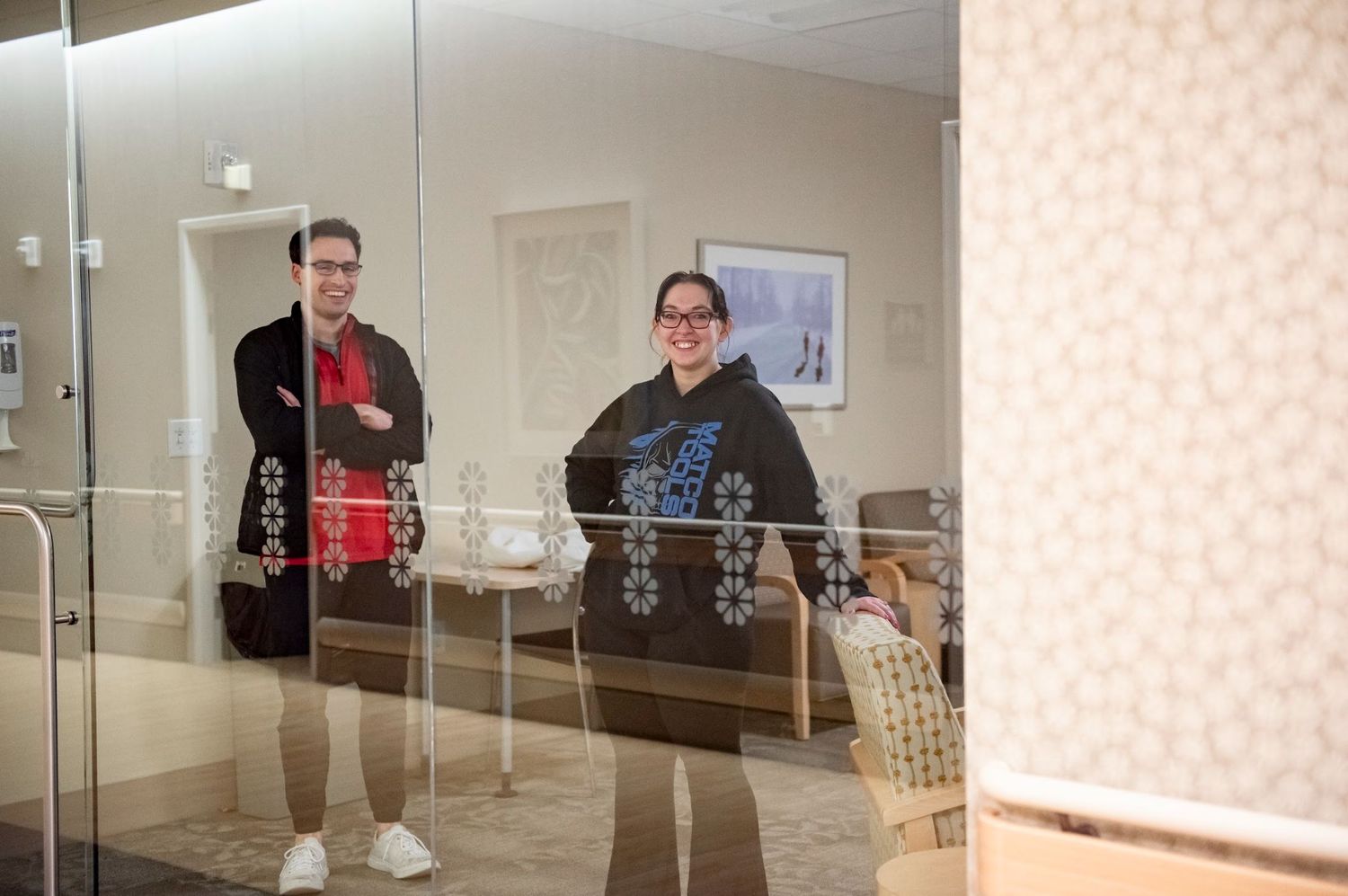 Two family members seen through glass window in hospital hallway waiting for a c-section