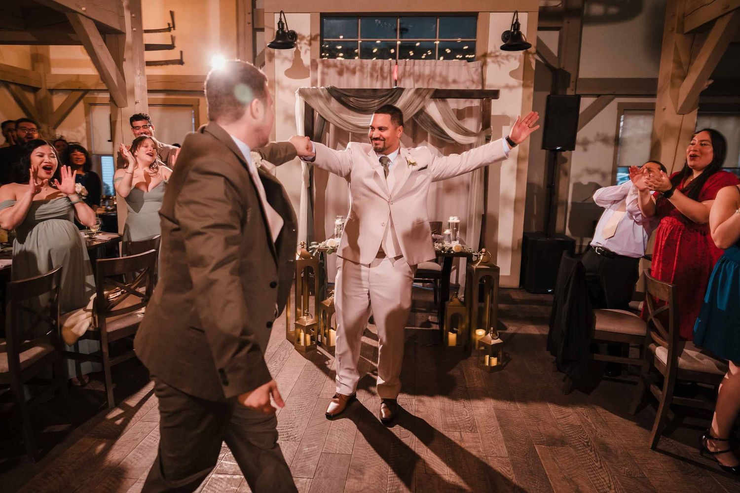 Grooms celebrating grand entrance with guests cheering at Briar Barn Inn wedding reception