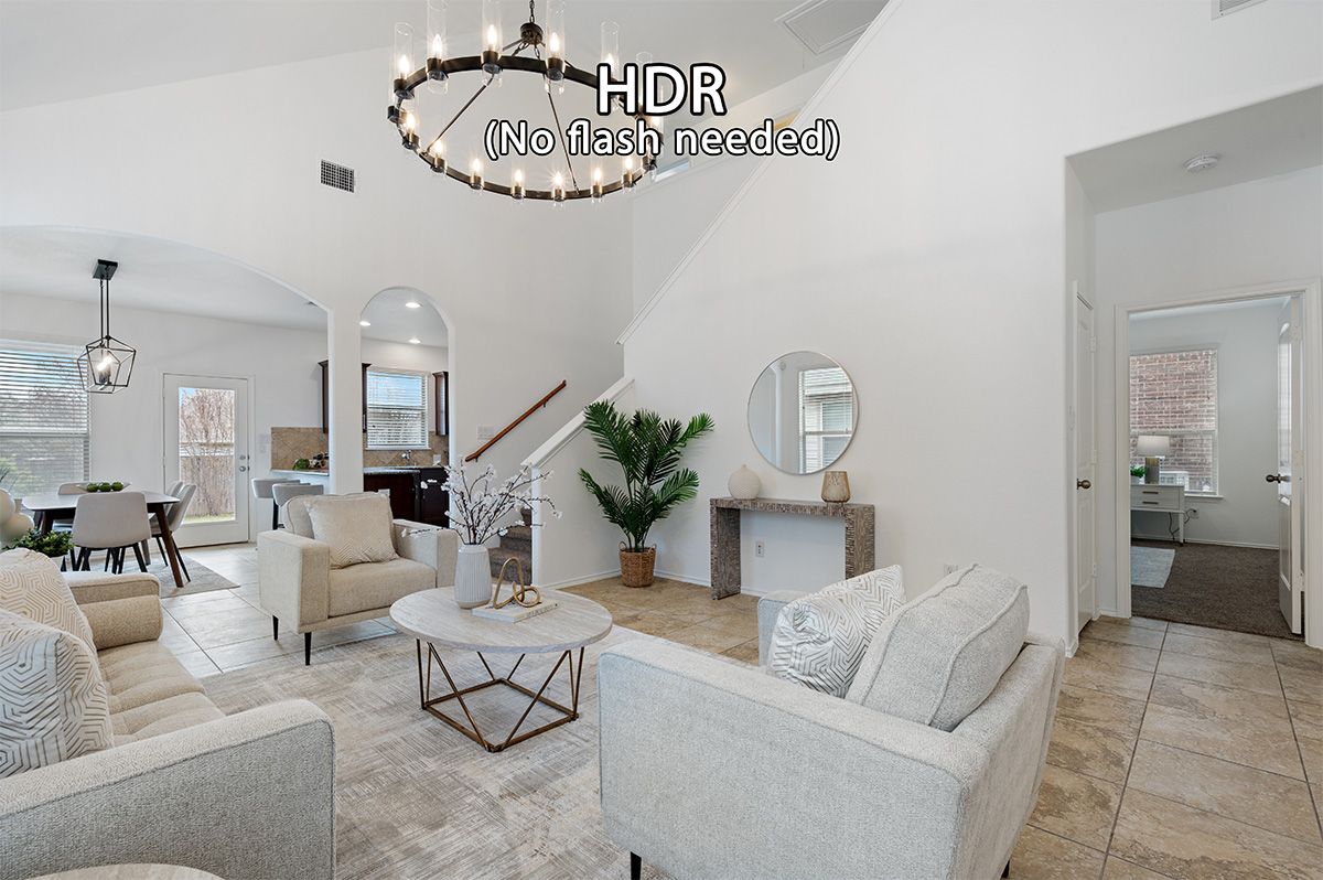 Bright open-concept living room with vaulted ceilings, neutral furnishings, chandelier, and staircase in a modern home.