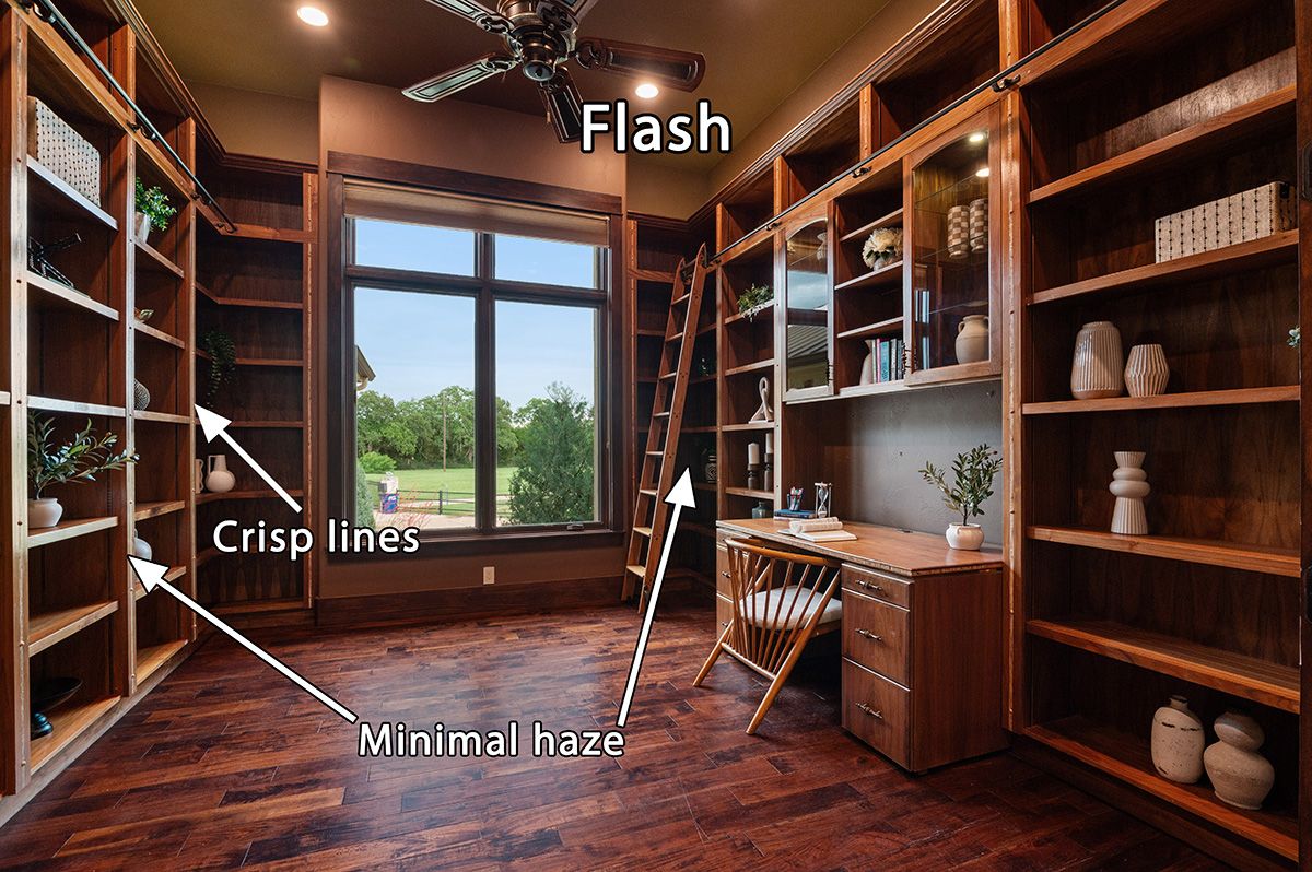Elegant home office with floor-to-ceiling wooden bookshelves, rolling ladder, hardwood floors, and large window with garden view.