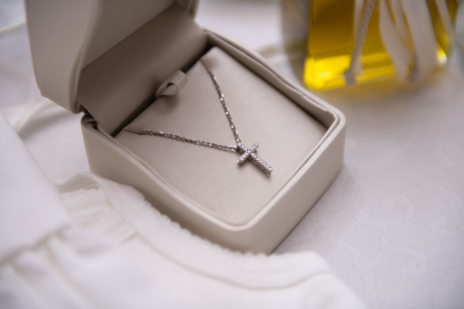 A silver cross necklace in a white jewelry box for a Christian baptism gift.