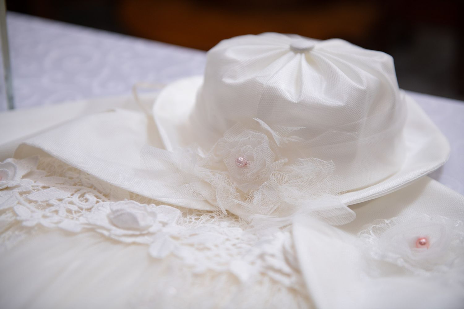 A white lace baptism gown and hat laid out for an Orthodox Christian christening ceremony.