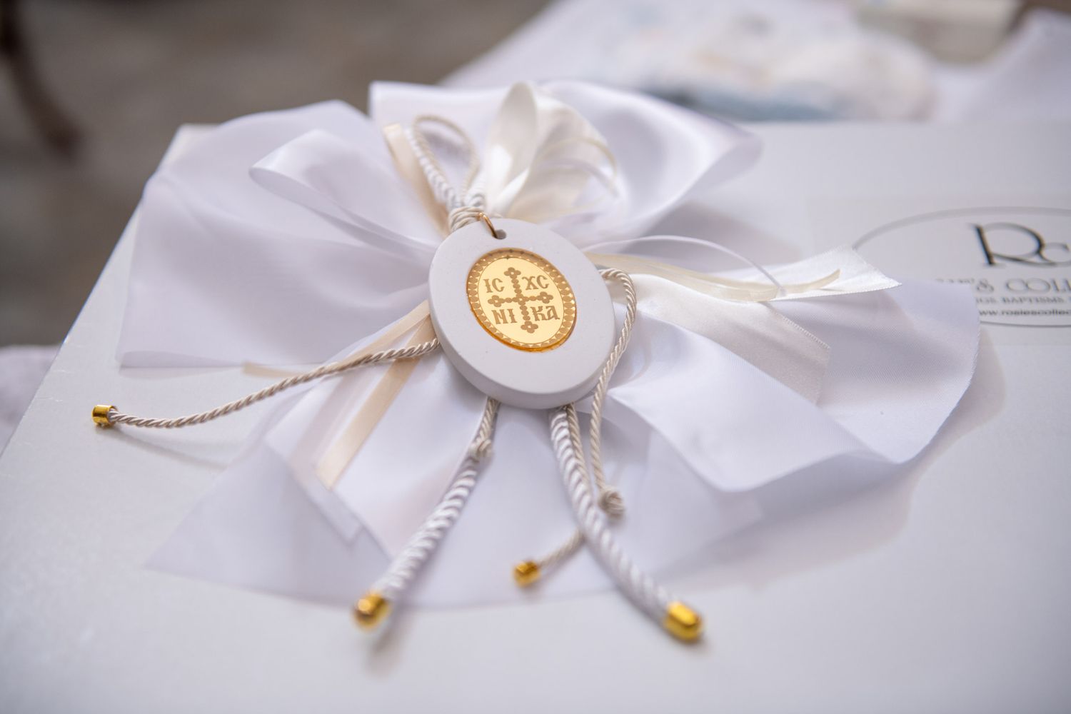 An elegant white satin Orthodox Christian baptism favor with gold cross medallion and ribbon bow.