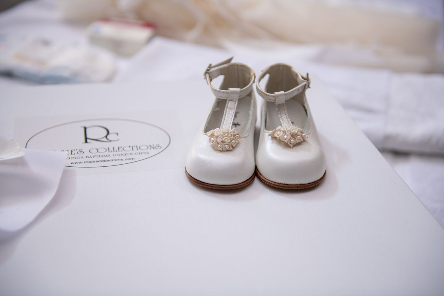 White pearl-embellished baby shoes on a box for an Orthodox Christian baptism ceremony.