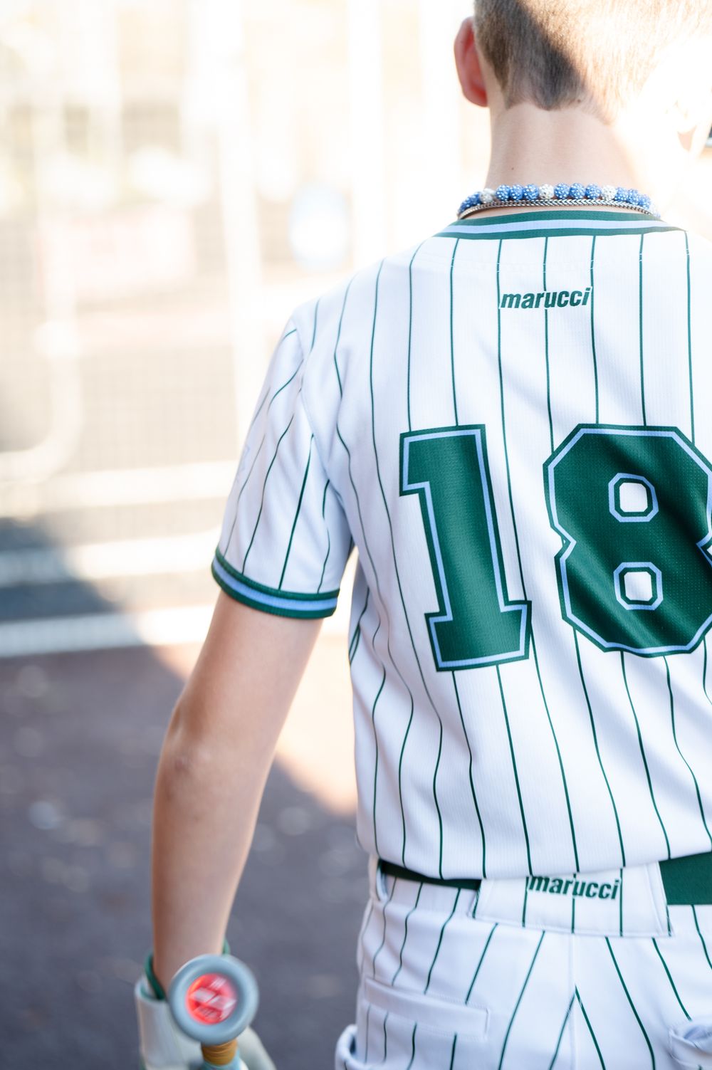 Close-up of baseball jersey with number 18 in white and teal pinstripes.