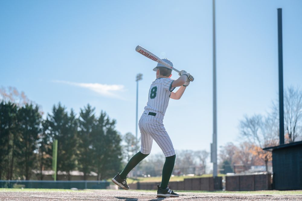 Baseball player in pinstriped uniform takes batting stance against bright blue sky.